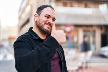 Fototapeta na wymiar Young hispanic man smiling confident doing ok sign with thumb up at street