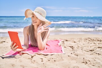 Young chinese girl having video call using touchpad at the beach.