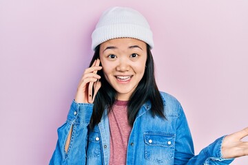 Young chinese girl having conversation talking on the smartphone celebrating achievement with happy smile and winner expression with raised hand