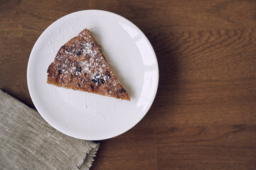 A delicious piece of lemongrass with blueberries and cranberries, without milk and eggs on flaxseed flour. Part of the pie is on a white plate on the table. The concept of healthy eating