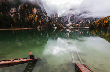 Beautiful autumn day by lake Braies in the Dolomites on a moody morning. Fog and clouds rolling over the mountains.