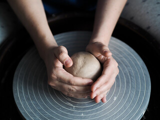 Ceramist young woman preparing clay to make pottery pieces in her studio; anonymous hands at work....