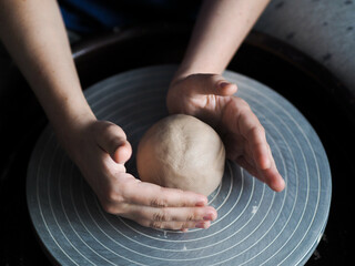 Ceramist young woman preparing clay to make pottery pieces in her studio; anonymous hands at work. Small business, hobby, ceramic concept.