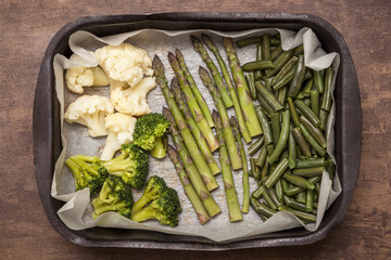 Baked vegetables asparagus, broccoli and cauliflower on parchment paper close up. Vegan healthy diet food concept