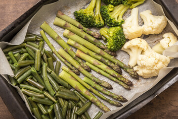 Baked vegetables asparagus, broccoli and cauliflower on parchment paper close-up. Vegan healthy diet food concept