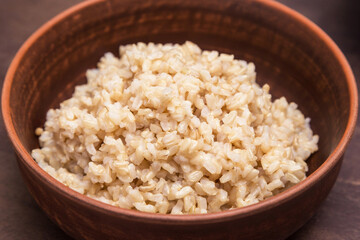 Boiled brown rice in a clay plate, bowl close-up