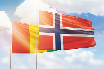 Sunny blue sky and flags of norway and guinea
