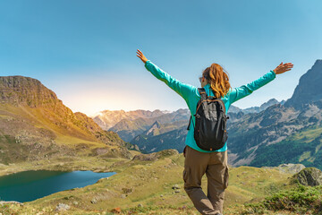 Attractive young woman with open arms enjoying life in the middle of a mountain with a lake in a beautiful landscape.