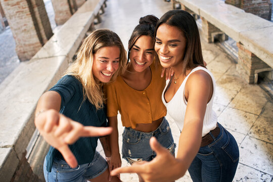 Three cheerful girls friends in summer clothes taking a selfie outdoors at the touristic urban center city