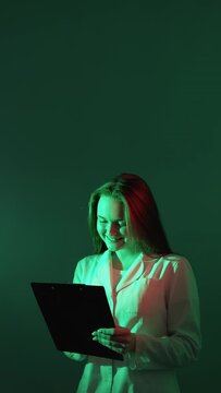 Inspired doctor. Aha moment. Therapy solution. Enthusiastic female physician raising finger taking notes in red green neon light isolated on teal vertical copy space background.