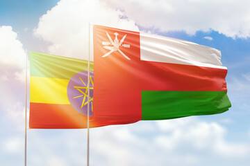 Sunny blue sky and flags of oman and ethiopia