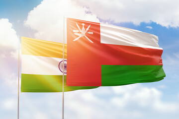 Sunny blue sky and flags of oman and india