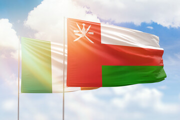 Sunny blue sky and flags of oman and ireland