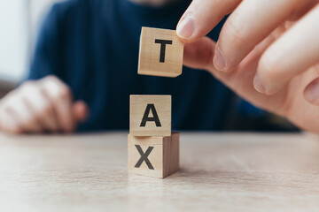 A hand from cubes makes a word tax. A government tool for transferring part of the money from income