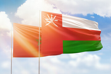 Sunny blue sky and flags of oman and morocco