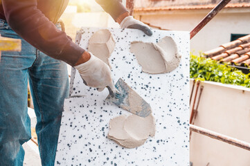 Mason applies glue to a thermal cladding on a construction site