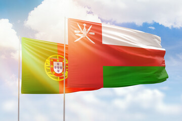 Sunny blue sky and flags of oman and portugal