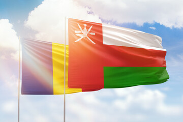 Sunny blue sky and flags of oman and romania