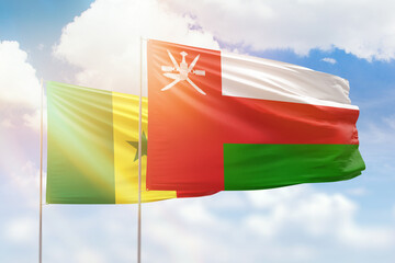Sunny blue sky and flags of oman and senegal