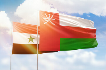 Sunny blue sky and flags of oman and syria