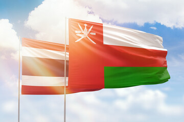 Sunny blue sky and flags of oman and thailand