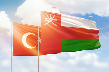 Sunny blue sky and flags of oman and turkey