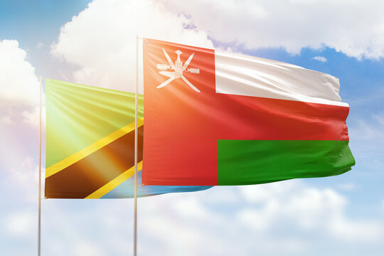 Sunny blue sky and flags of oman and tanzania