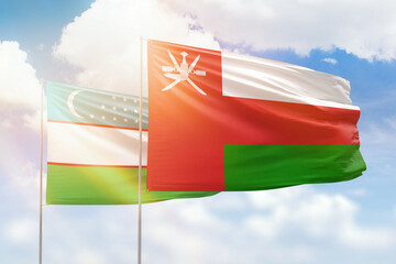Sunny blue sky and flags of oman and uzbekistan