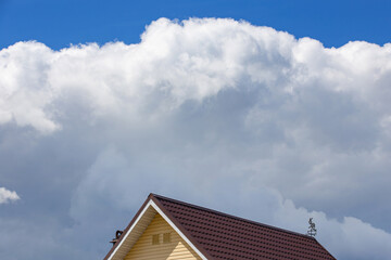 the roof of a residential building against a blue sky with clouds