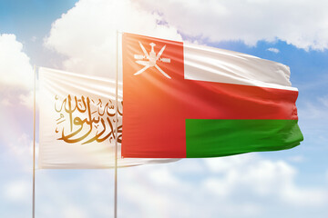Sunny blue sky and flags of oman and afghanistan