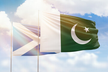 Sunny blue sky and flags of pakistan and scotland