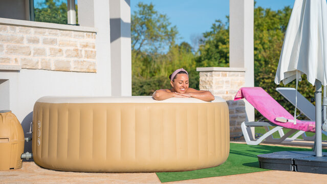 Girl in an inflatable jacuzzi in front of the house.