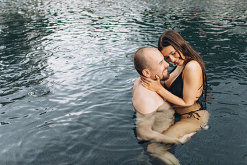 Fototapeta premium Couple in love swimming together in the sea under the warm summer rain