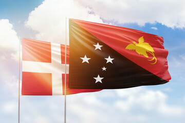 Sunny blue sky and flags of papua new guinea and denmark