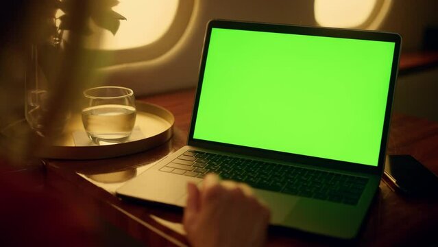 Woman watch green laptop screen on first class flight. Hands touch pad closeup