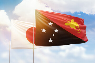 Sunny blue sky and flags of papua new guinea and japan
