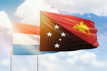 Sunny blue sky and flags of papua new guinea and luxembourg