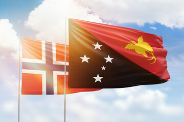 Sunny blue sky and flags of papua new guinea and norway