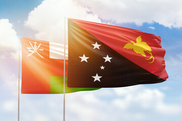 Sunny blue sky and flags of papua new guinea and oman