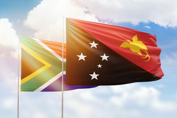 Sunny blue sky and flags of papua new guinea and south africa