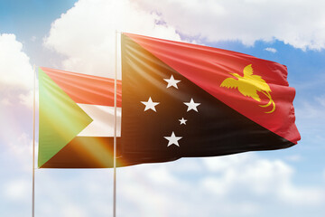 Sunny blue sky and flags of papua new guinea and sudan