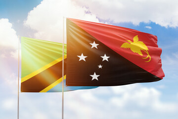 Sunny blue sky and flags of papua new guinea and tanzania