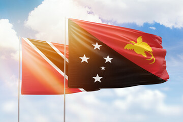 Sunny blue sky and flags of papua new guinea and trinidad and tobago