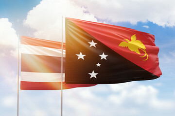 Sunny blue sky and flags of papua new guinea and thailand