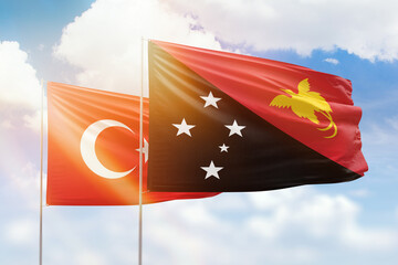 Sunny blue sky and flags of papua new guinea and turkey
