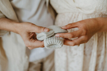 Mains de parents tenant des chaussettes de bébé nouveau né dans une chambre d'enfant