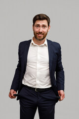 Fototapeta premium Businessman showing his empty pockets standing on grey studio background
