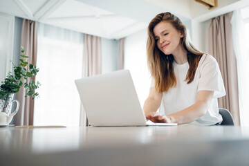 Fototapeta premium A woman uses a laptop computer at home online training, education remotely on the school's website