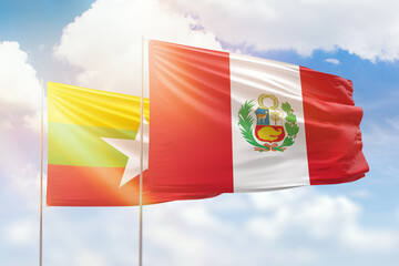 Sunny blue sky and flags of peru and myanmar