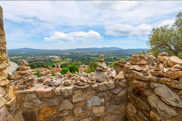 Fototapeta na wymiar Stones stacked and balanced on top of each other on the ancient wall of the Chateau de Grimaud with the hills of the Cote d'Azur in view in Grimaud, France.